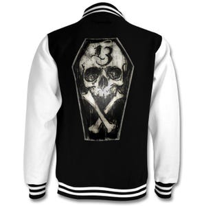 May include: Black and white varsity jacket with a skull and crossbones design in a coffin. The skull has the number "13" on its forehead.