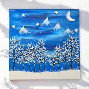 Może przedstawiać: Kwadratowy obraz przedstawiający zimowy krajobraz pod gwiaździstym niebem. Białe, ośnieżone drzewa i góry na niebieskim tle. Półksiężyc i akcenty w kształcie gwiazd dopełniają zimowy motyw. Podpis artysty w lewym górnym rogu.