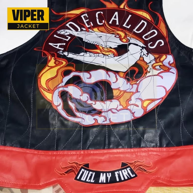 Puede incluir: Chaleco de cuero negro con un parche bordado rojo y amarillo que dice "ALDE CALDOS" con una calavera y llamas. El chaleco tiene un fondo rojo con un parche negro que dice "FUEL MY FIRE".
