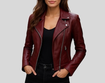 May include: A burgundy leather jacket with a classic asymmetrical zip closure, a notched collar, and zippered pockets. The jacket has long sleeves and a tailored fit. The model is wearing a black top and dark jeans.