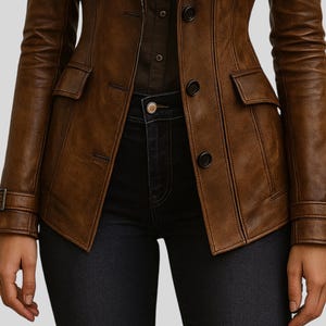 May include: A brown leather jacket with a tailored fit, featuring a button-down front, two front pockets, and adjustable cuffs. The jacket is worn with dark denim jeans, creating a classic and stylish look.