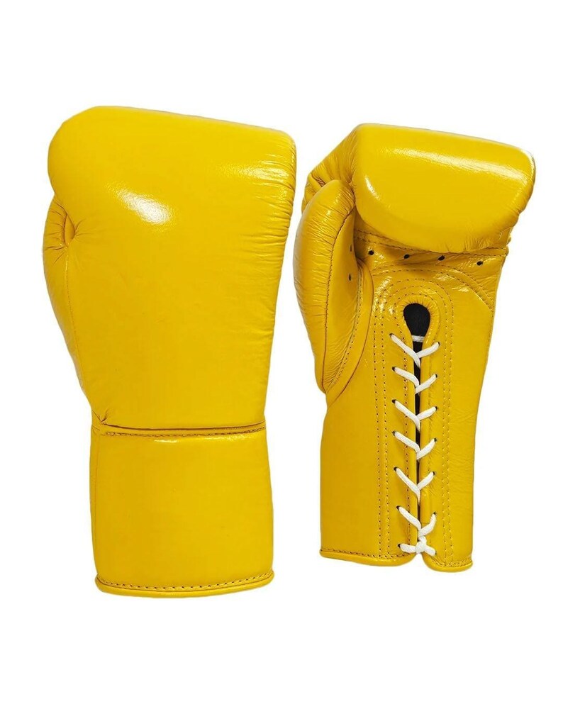 May include: A pair of bright yellow boxing gloves. The gloves are made of leather and have a glossy finish. White laces secure the gloves. The gloves are designed for protection and impact absorption during boxing.