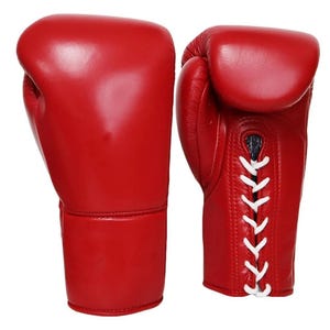 May include: A pair of bright red boxing gloves. The gloves are made of smooth leather and feature white laces. The design includes a padded area for the knuckles and a cuff for wrist support. The gloves are designed for boxing or other combat sports.