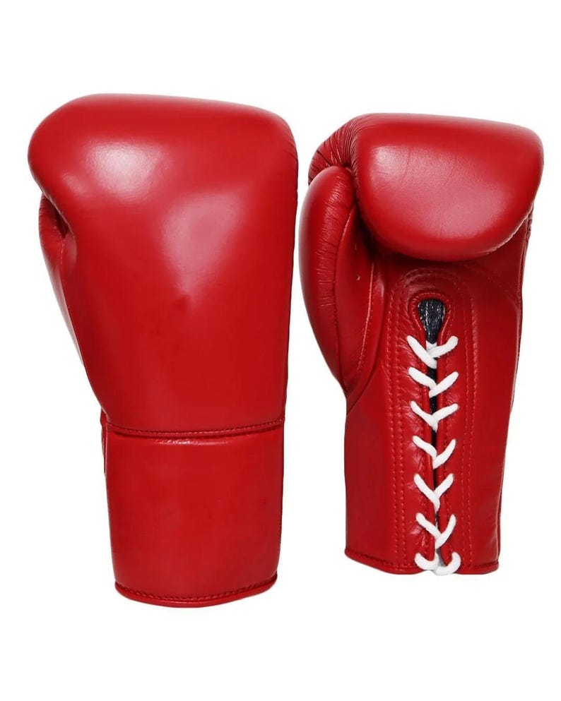 May include: A pair of bright red boxing gloves. The gloves are made of smooth leather and feature white laces. The design includes a padded area for the knuckles and a cuff for wrist support. The gloves are designed for boxing or other combat sports.
