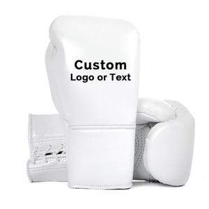 May include: Two white boxing gloves are displayed against a white background. The gloves are made of a smooth material and feature the text "Custom Logo or Text" on the front. The gloves are designed for boxing or other combat sports.