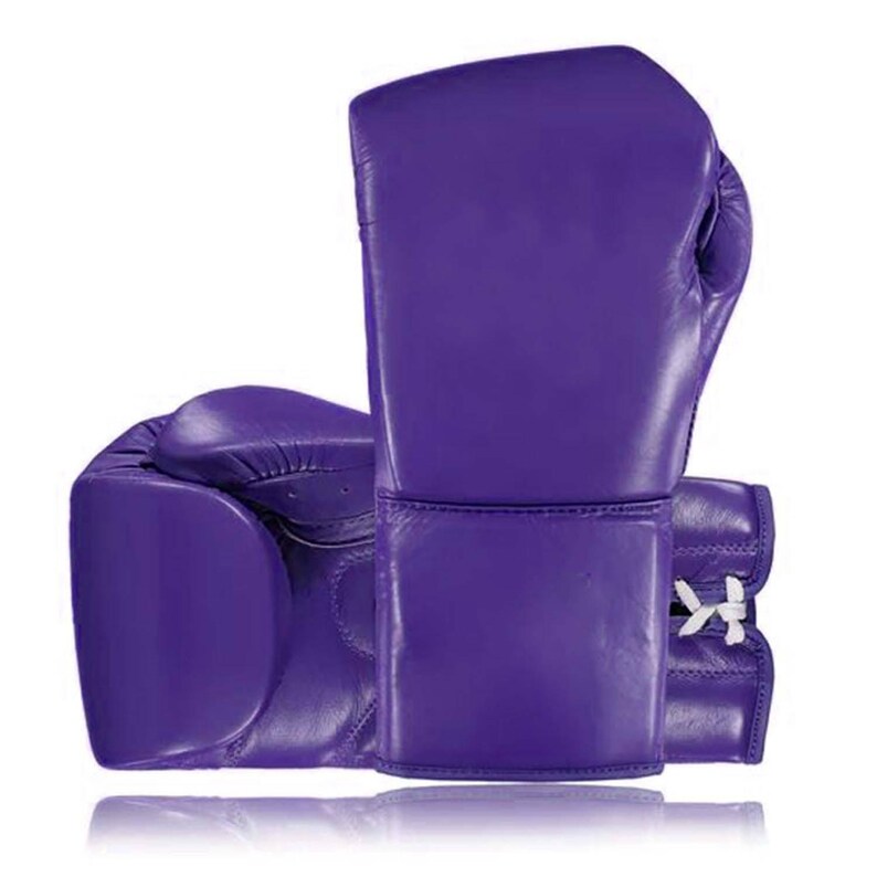 May include: A pair of vibrant purple boxing gloves. The gloves are made of leather and feature a classic design with padded knuckles and wrist support. White laces secure the wrist area. The gloves are designed for training and competition.