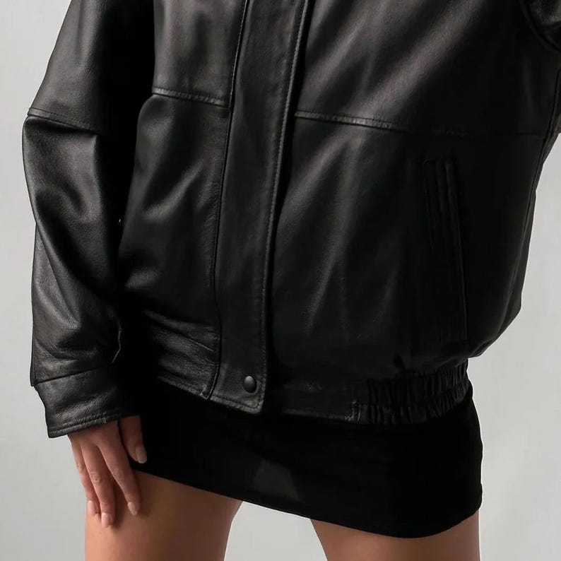 Pode incluir: Casaco de couro preto estilo bomber. O casaco apresenta bainha e punhos canelados, fecho de bot&atilde;o e gola cl&aacute;ssica. A pe&ccedil;a &eacute; usada com uma minissaia preta.
