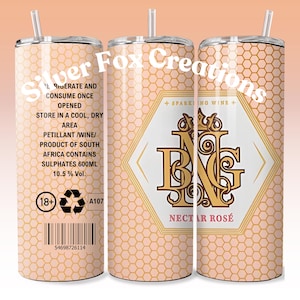 Puede incluir: Un juego de tres vasos de acero inoxidable con un patrón de panal y un diseño dorado. Los vasos están etiquetados como "Sparkling Wine" y "Nectar Rosé".