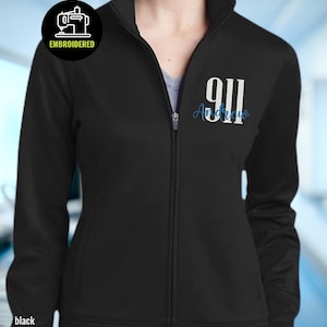 May include: Black zip-up jacket with the number "911" in white and the name "Andrew" in blue script. The jacket has a high collar and a small embroidered patch with a sewing machine icon. The word "black" is printed at the bottom.