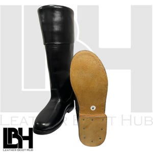 Könnte beinhalten: Ein Paar schwarze, kniehohe Lederstiefel mit brauner Ledersohle. Die Stiefel haben eine spitze Zehenpartie und einen Reißverschluss an der Innenseite des Stiefels.