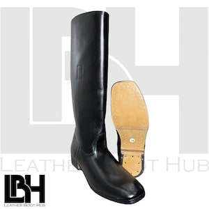 Könnte beinhalten: Schwarzer Lederreitstiefel mit hohem Schaft und eckiger Spitze. Die Sohle ist sichtbar, hellbraun mit kleinen Nägeln. Der Stiefel ist für Reitaktivitäten konzipiert.