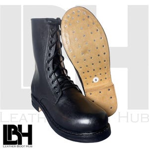 Könnte beinhalten: Schwarzer Leder-Kampfstiefel mit Schnürung. Die Sohle ist sichtbar und zeigt die Größe 9. Der Stiefel wird neben seiner Sohle präsentiert, um die Konstruktion und die Materialien zu zeigen.