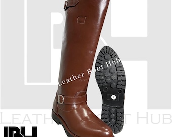 Puede incluir: Bota alta de cuero marrón con hebillas. La suela es negra y texturizada. La imagen también muestra la suela de la bota. El texto "Leather Boot Hub" es visible. Adecuada para actividades ecuestres.