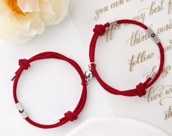 Puede incluir: Dos pulseras de cuerda roja con dijes de plata. Un dije tiene un símbolo de sol y el otro tiene un símbolo de luna.