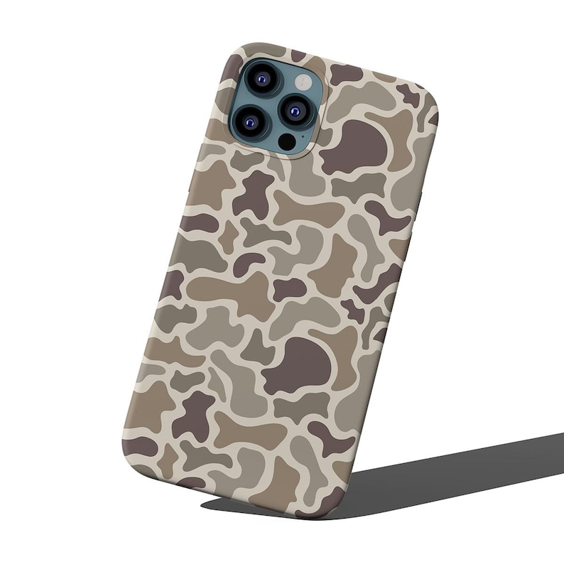 May include: A phone case with a camouflage pattern in shades of brown, tan, and gray. The case has a smooth finish and a camera cutout with multiple lenses. The design is a repeating pattern of organic shapes.