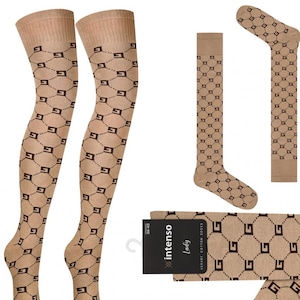 Può includere: Un paio di calze beige alte fino alla coscia con un motivo geometrico marrone. Le calze hanno un motivo ripetuto di G intrecciati. Le calze sono mostrate con un paio di calze abbinate in posizione piegata.