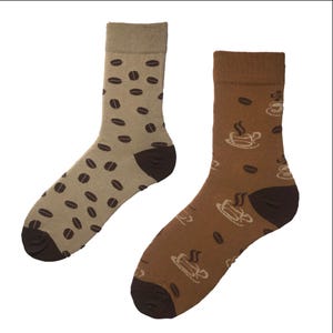 Puede incluir: Un par de calcetines marrones y beige con un diseño de granos de café y tazas de café.