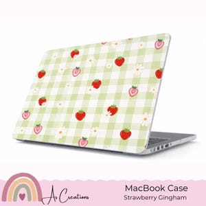 Könnte beinhalten: Eine MacBook-Hülle mit hellgrünem Vichy-Muster, verziert mit roten Erdbeeren und weißen Gänseblümchen. Die Hülle ist für einen Laptop konzipiert und trägt die Aufschrift "MacBook Case" und "Strawberry Gingham".