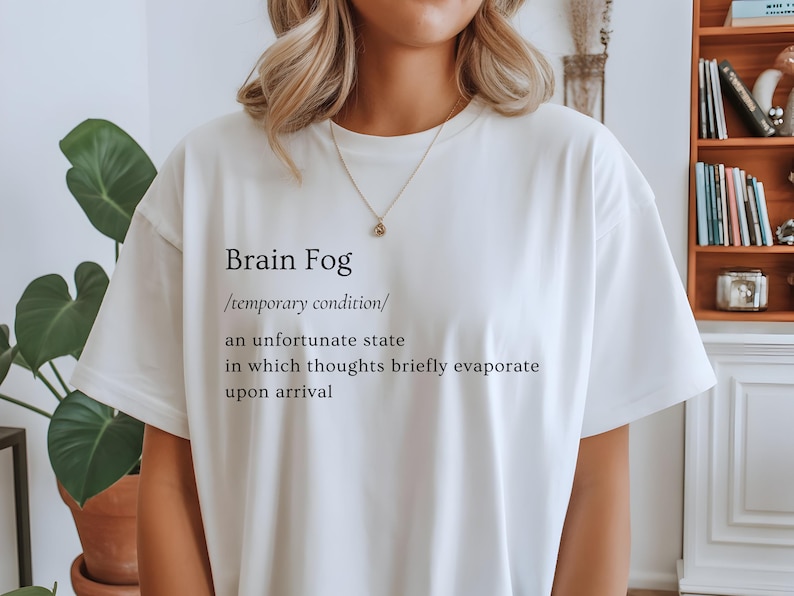Puede incluir: Camiseta blanca con la frase "Brain Fog" y una definici&oacute;n impresa en negro. La definici&oacute;n describe una condici&oacute;n temporal donde los pensamientos se evaporan brevemente. Una prenda casual para el d&iacute;a a d&iacute;a.