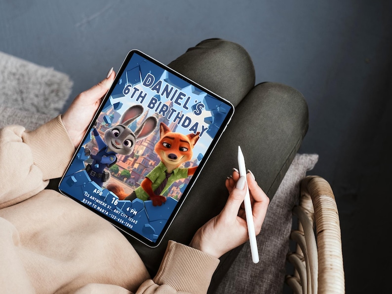 May include: A digital tablet displays a birthday invitation featuring cartoon characters Judy Hopps and Nick Wilde from Zootopia. The invitation reads "Daniel's 6th Birthday" with date and time details. The tablet is held by a person.