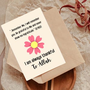 K&ouml;nnte beinhalten: Eine Gru&szlig;karte mit einer rosa Blume und einem gelben Zentrum sowie dem Text "I am always thankful To Allah". Die Karte liegt auf einem braunen Umschlag, mit einem Text aus dem Koran.
