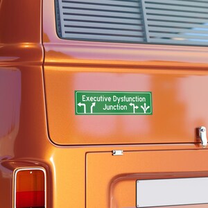 May include: A vintage orange van with a green sticker that reads "Executive Dysfunction Junction" with arrows pointing in multiple directions.