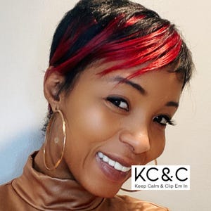 May include: A woman with short, black and red hair is smiling. She is wearing large gold hoop earrings and a brown leather jacket. The text "KC&C Keep Calm & Clip Em In" is visible in the lower right corner of the image.