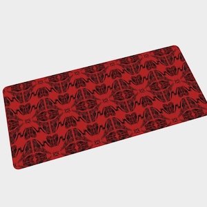 Peut inclure: Un tapis de bureau rectangulaire présentant un motif répétitif de formes abstraites et symétriques noires sur un fond rouge vif. Le design se compose de lignes entrelacées et de formes courbes créant une texture graphique dense et uniforme.