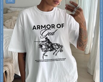 May include: White t-shirt with the text "ARMOR OF God" above a black and white illustration of a knight on horseback. Below the illustration are the words "BELT OF TRUTH | BREASTPLATE OF RIGHTEOUSNESS | SHOES OF PEACE | SHIELD OF FAITH | HELMET OF SALVATION | SWORD OF THE SPIRIT."