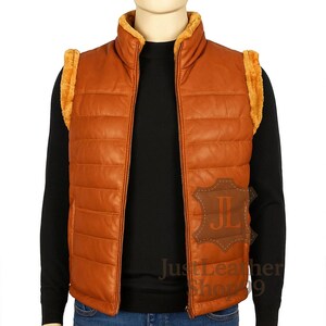 May include: A brown leather gilet with a high collar and a full-length zip. The gilet features tan-coloured faux fur trim on the collar and shoulders. The text "Just Leather Shop 9" is visible on the lower right side.