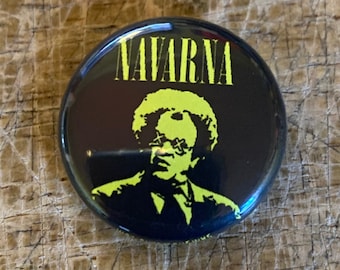 May include: A black and yellow button with a silhouette of a person wearing sunglasses and the word "NAVARNA" in yellow letters.