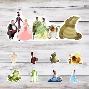 May include: A collection of colorful stickers featuring characters from a fairy tale. The stickers include a princess in a pink gown, a frog, a crocodile, and other characters. The stickers are on a light wood grain background.