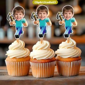 May include: Three cupcakes with vanilla frosting, each topped with a Minecraft-themed character holding a pickaxe. The character's face is a photo of a young boy. The cupcakes are in paper liners and sit on a wooden surface. The image includes the text "ClipArtStudio63".