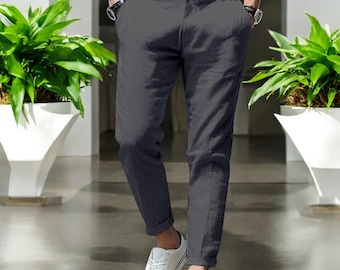 May include: A pair of dark gray linen pants with a straight leg fit. The pants have a button and zipper closure and belt loops. The model is wearing the pants with white sneakers.