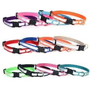 May include: A collection of adjustable pet collars in various colors including purple, pink, blue, orange, red, beige, green, and teal. Each collar features a reflective silver strip, a black plastic side-release buckle, and a metal D-ring.