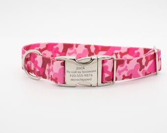 May include: Pink dog collar with a bone-shaped camouflage pattern. The collar has a silver metal buckle with engraved text. The text reads "Jack, Plz call my hoomans, 920-555-9876, microchipped."