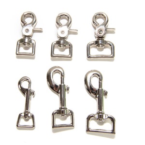 May include: Six silver metal clasps of varying sizes. The clasps are all the same design, with a loop on one end and a hook on the other. The clasps are commonly used for attaching leashes, straps, or other items.