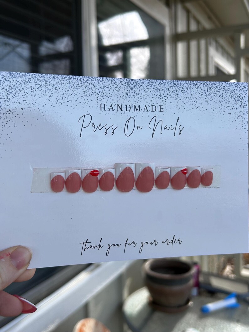 K&ouml;nnte beinhalten: Ein Set handgefertigter Press-On-N&auml;gel in einem ged&auml;mpften Rosaton mit gl&auml;nzendem Finish. Die N&auml;gel sind auf einer wei&szlig;en Karte mit den Worten "HANDMADE Press On Nails" und "thank you for your order" angeordnet.