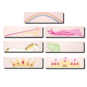 May include: Set of seven pink and yellow illustrated wall decals featuring a rainbow, a princess dress, a horse, a frog, a crown, a castle, and a star.