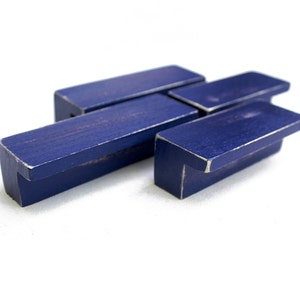 May include: Three blue wooden drawer pulls with a distressed finish. The pulls are shaped like a small bench with a rectangular top and a curved front.