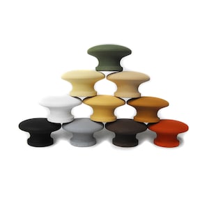 May include: A set of ten round cabinet knobs in various colors, including black, white, gray, brown, orange, green, and beige. The knobs are arranged in a pyramid shape.
