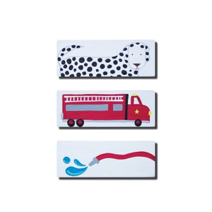 May include: Three wooden wall art pieces with a black and white dalmatian dog, a red fire truck, and a red fire hose with blue water droplets.