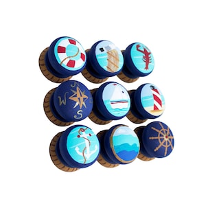 May include: Ten blue and brown wooden knobs with nautical themed designs. The designs include a life preserver, lighthouse, sailboat, anchor, compass, lobster, and a ship's wheel.