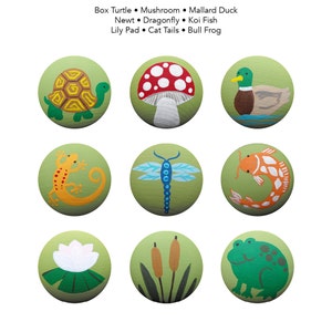 Op de afbeelding: Negen beschilderde stenen met verschillende natuurthema's. De ontwerpen omvatten een ​​schildpad, een paddenstoel, een wilde eend, een salamander, een libel, een koi-vis, een waterlelie, lisdodde en een stier kikker.