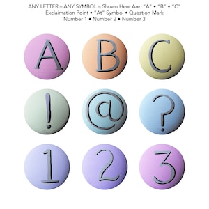May include: Nine round, painted, wooden discs with different letters, symbols, and numbers on them. The letters are A, B, and C. The symbols are an exclamation mark, an at symbol, and a question mark. The numbers are 1, 2, and 3.