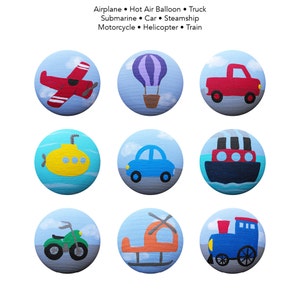 May include: Nine painted wooden circles, each depicting a different mode of transportation. The circles are arranged in three rows of three. The top row features a red airplane, a purple hot air balloon, and a red pickup truck. The middle row features a yellow submarine, a blue car, and a blue steamship. The bottom row features a green motorcycle, an orange helicopter, and a blue train.