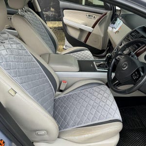 以下が含まれることがあります： ダイヤモンド柄のグレーとブラックの車のシートカバー。カバーは車のフロントシートに取り付けられています。