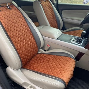 以下が含まれることがあります： ダイヤモンド柄のブラウンのキルティングされた車のシートカバー。カバーは車のフロントシートに取り付けられています。