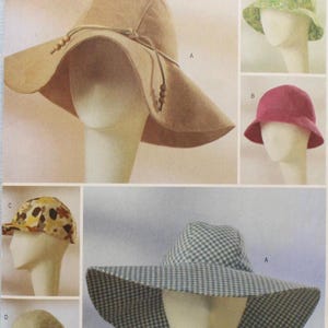May include: A Butterick pattern sheet featuring various hat designs. The main hat is a wide-brimmed, tan-colored hat with a drawstring. Other hats include a green floral, a pink cloche, a patterned cap, and a gingham sun hat.