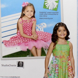May include: Simplicity sewing pattern number 1821 for a girl's dress. The pattern includes two dress styles, one with polka dots and a tulle skirt and the other with a patchwork design. The pattern is for sizes 3-8.